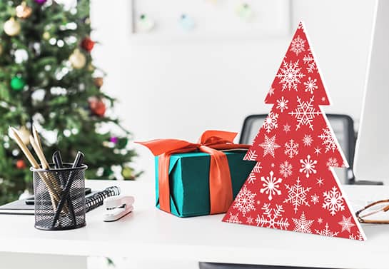 Red and white Christmas tree sign made of plastic material placed on a desk