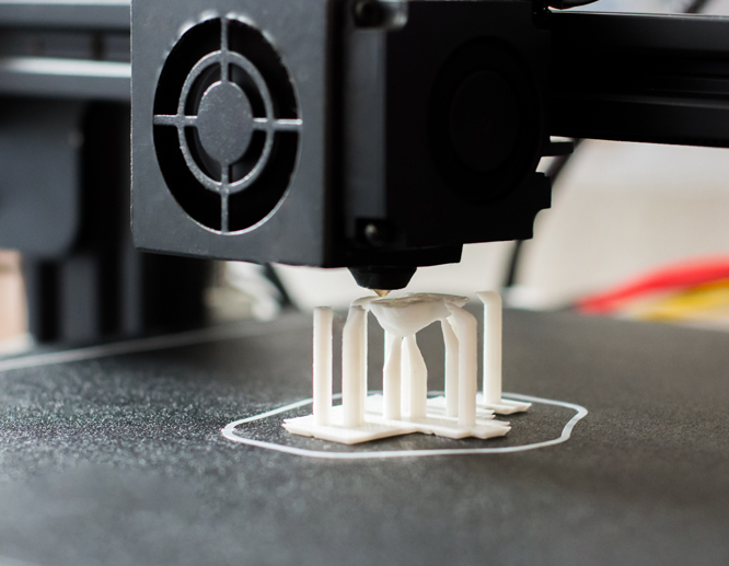 3D printer creating white architectural model structure with precision layering.