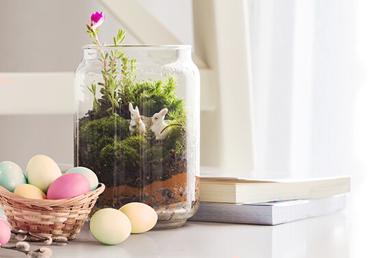 Easter decoration idea with a glass vase filled with grass and bunnies