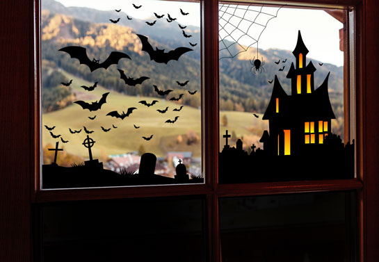 Holiday window idea for Halloween with a witch house and bats