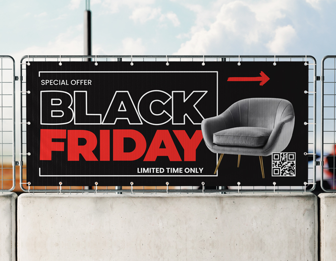 A Black Friday vinyl banner mounted to a fence outdoors announcing sales at a furniture store.