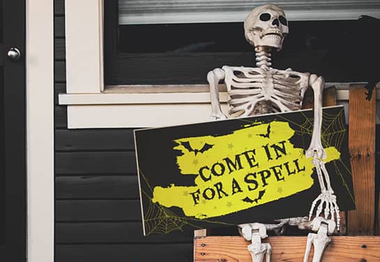 Halloween porch sign with a creepy message put in a skeleton's hand