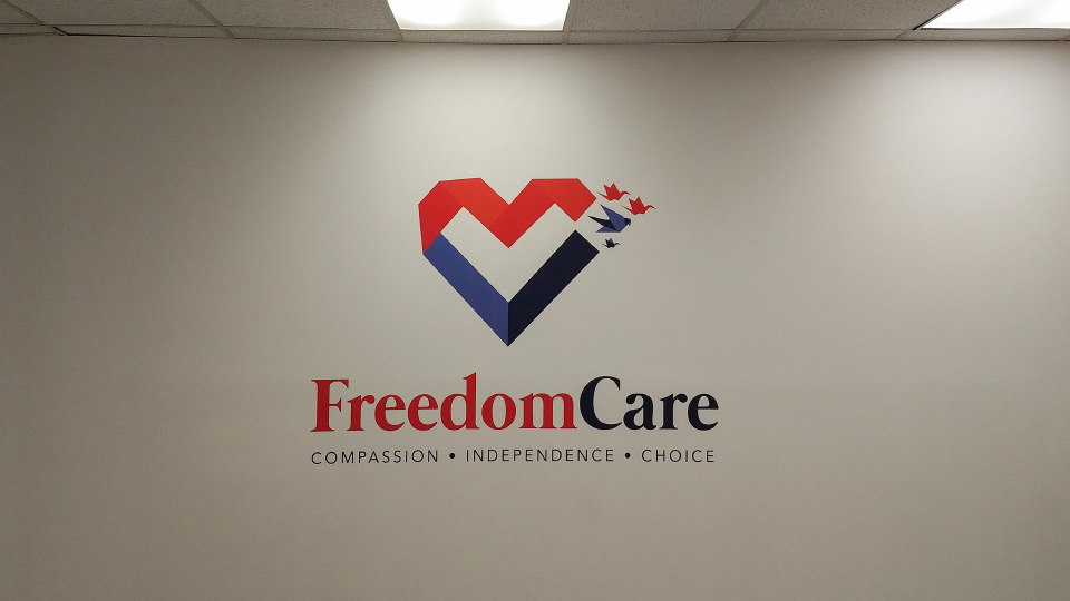 Freedom Care vinyl wall lettering in red and blue tones displaying the brand name and logo