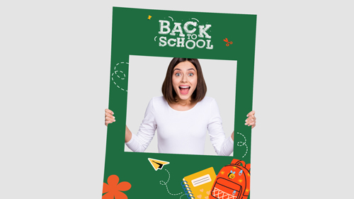 Happy woman holding green back to school selfie frame with school supplies design.
