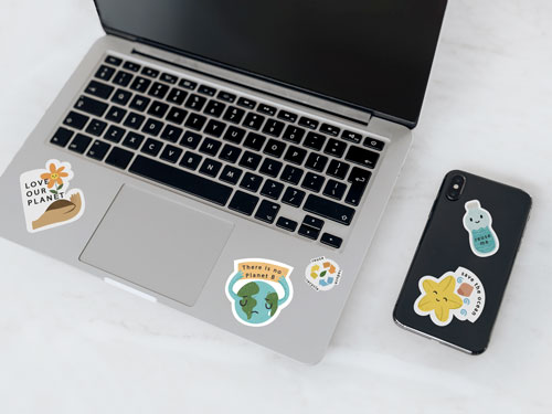 Eco-friendly kiss cut stickers with 'Save the Planet' messages, on a laptop and a phone.