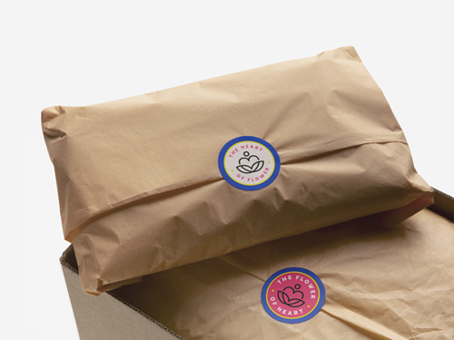 Circle kiss cut stickers displaying the brand name and logo, presented on wood-patterned packaging.