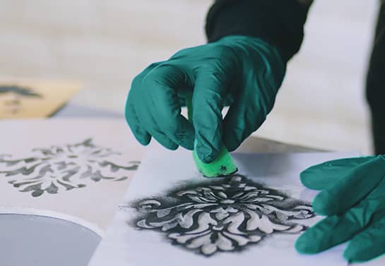 a man wearing gloves showing how to make wooden signs with stencils