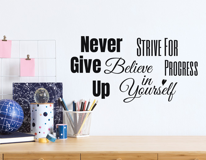 A mix of motivational bedroom wall sayings above a desk
