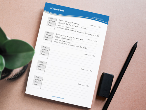 Corporate notepad printing with task sections and a blue header, accompanied by a pen and eraser on a desk