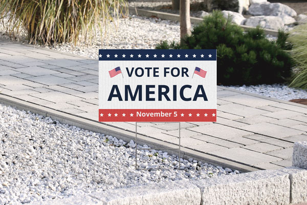 Corrugated plastic sign reading Vote For America with flags on both sides.