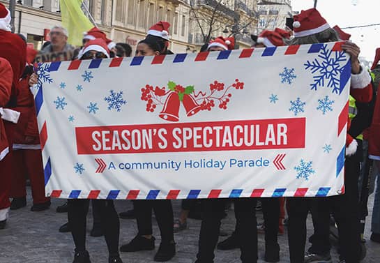 An exterior community holiday parade banner with the name 'Season's Spectacular'