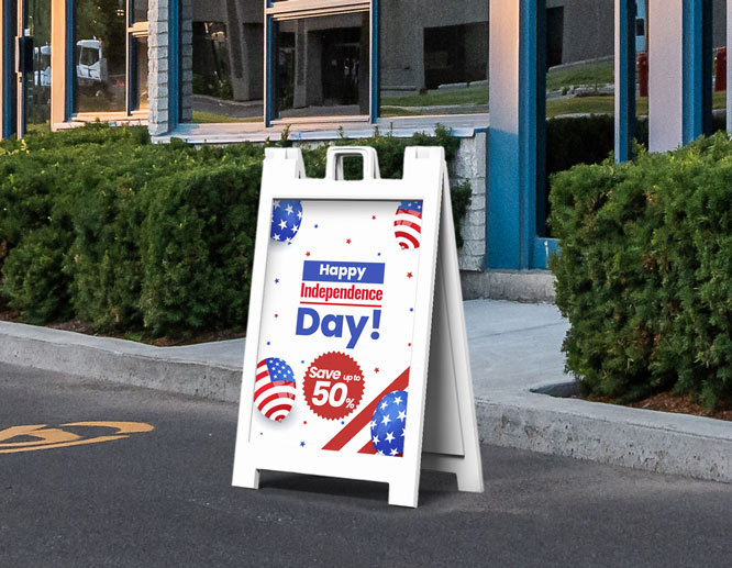 Storefront 4th of July sandwich board displaying balloons in American flag colors and a quote