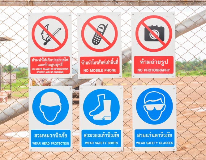 Examples of safety signs with different notes fixed to a fence around a construction zone.