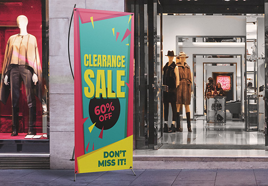 Clearance sale sign with yellow lettering placed in front of a clothing store