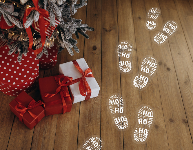 Unique floor decals next to the Christmas tree and gift boxes that resemble Santa's booprints and reads "Ho Ho Ho"