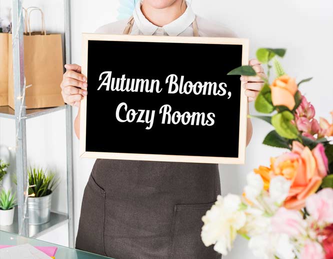 Florist holding chalkboard sign with the phrase “Autumn Blooms, Cozy Rooms,” promoting creative seasonal slogan ideas.