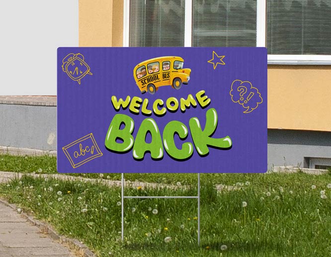 First day of school yard sign displaying a school bus and reading Welcome Back